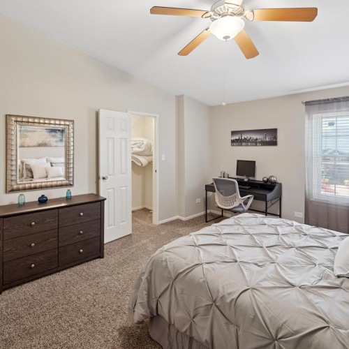 a bedroom with a ceiling fan and a large window